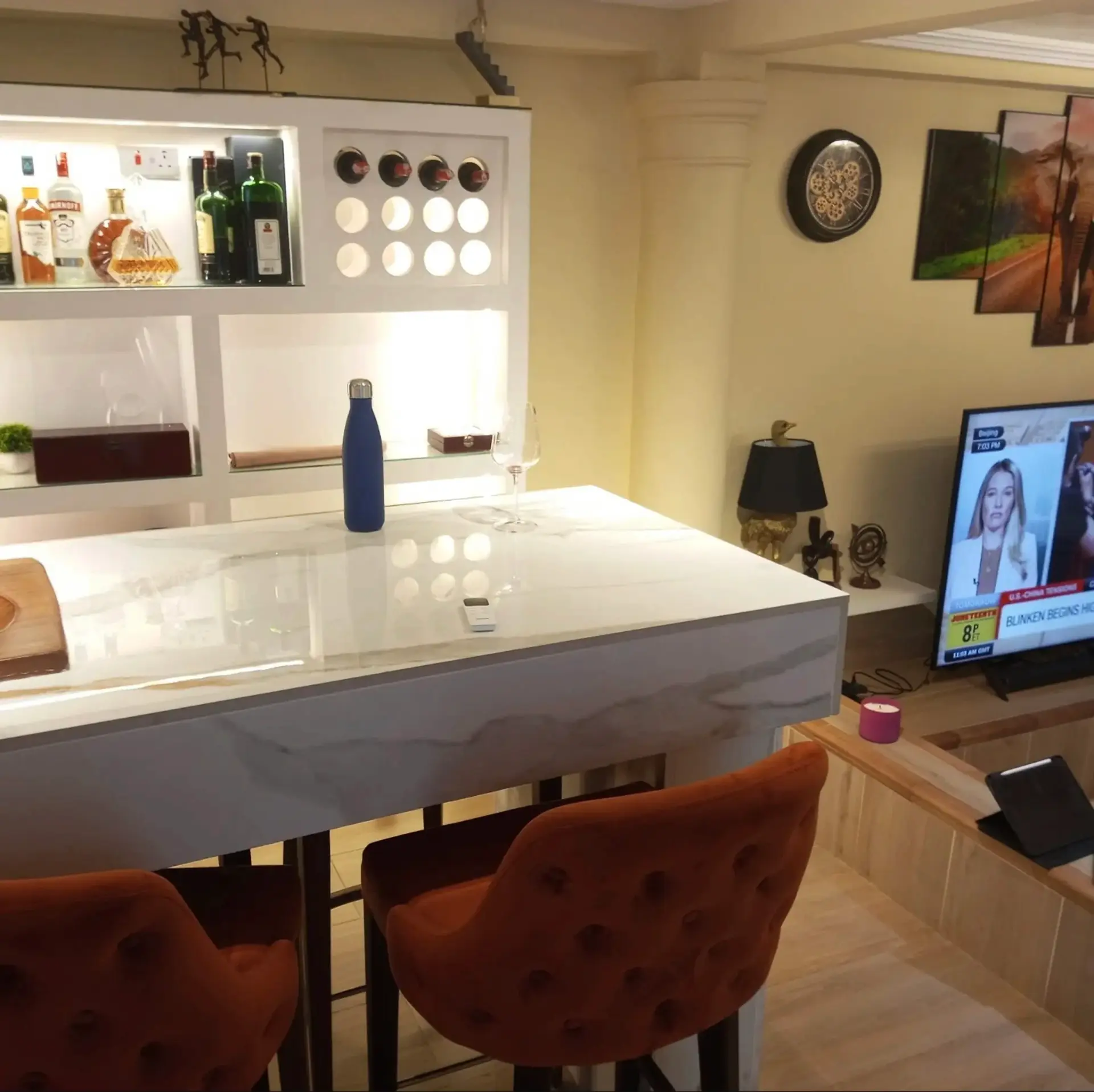 Marble bar counter with velvet stools and a stocked drinks shelf
