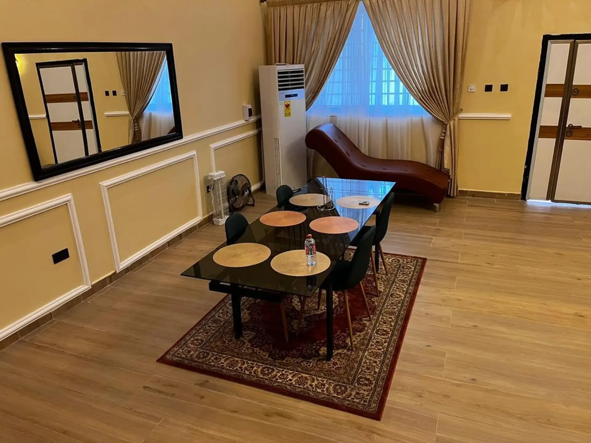 Glass dining table for six on a patterned rug beside a leather chaise