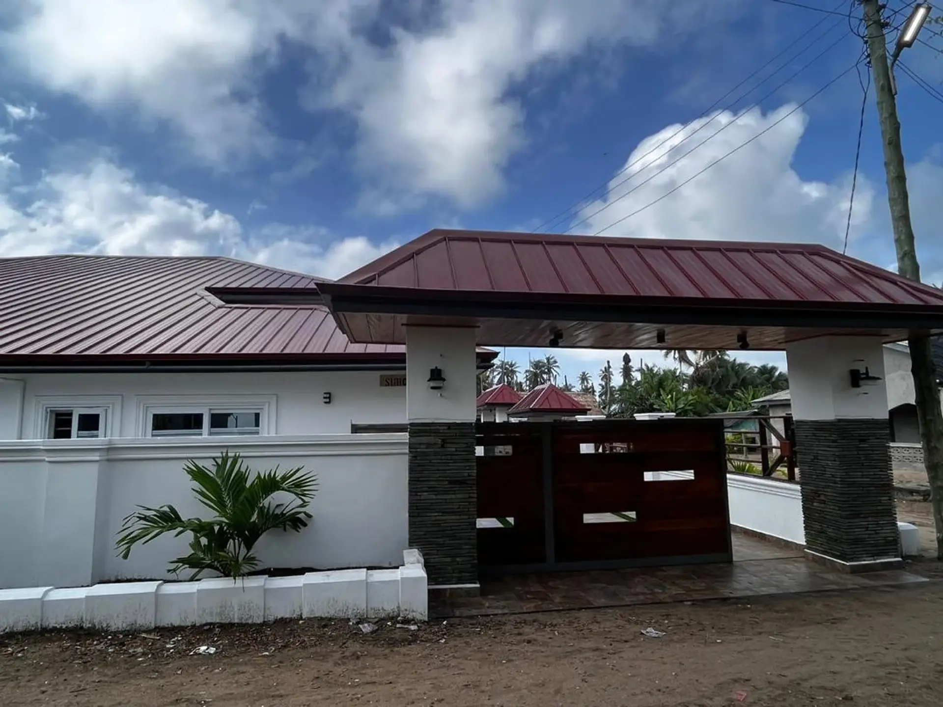 The gated entrance of Suhone Villa under a bright blue sky