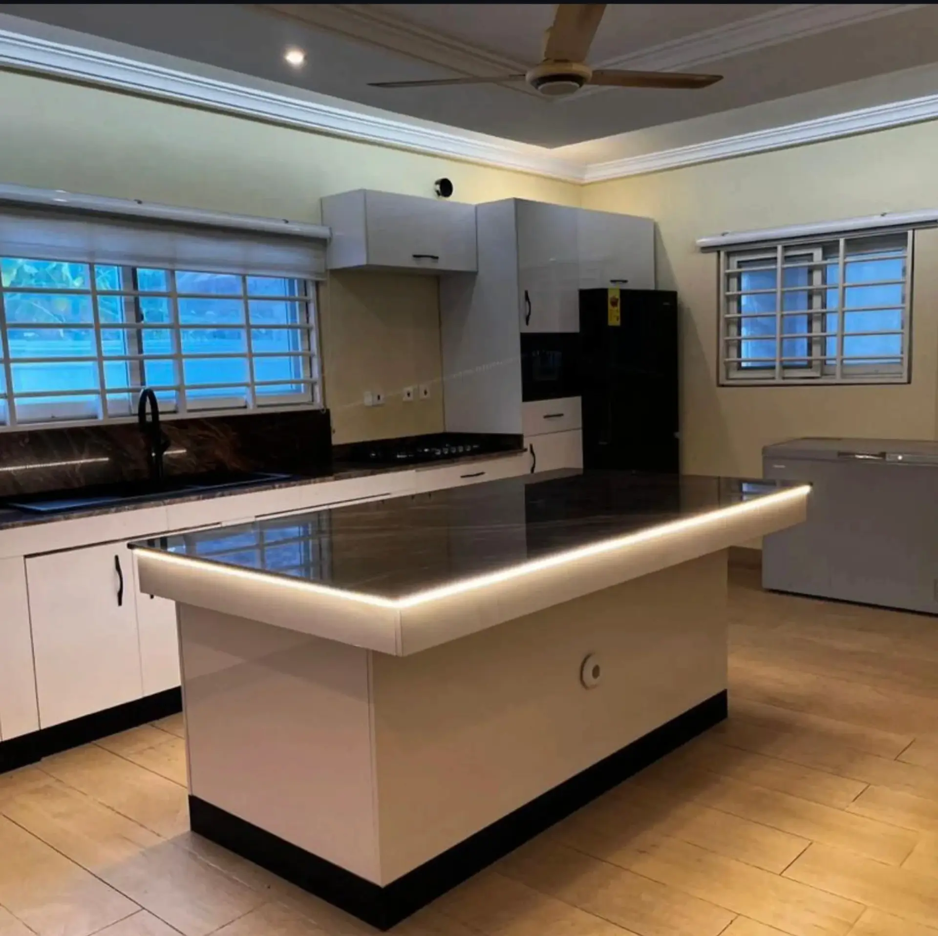 Wide view of the villa kitchen with wooden cabinetry, gas range and prep island