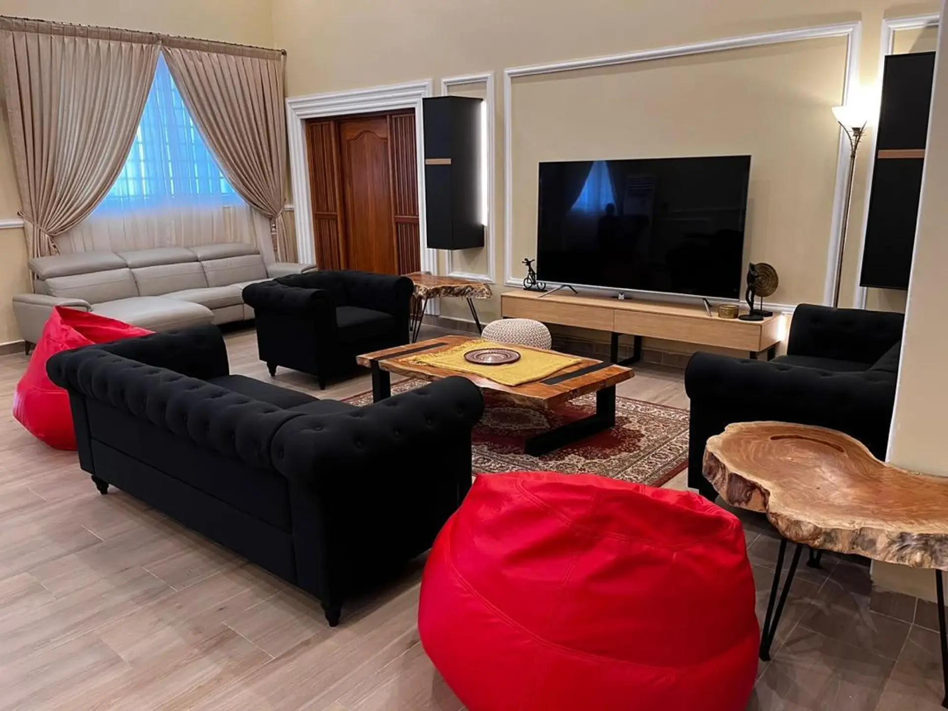 Living lounge with black Chesterfield sofas, a live-edge coffee table and a large TV