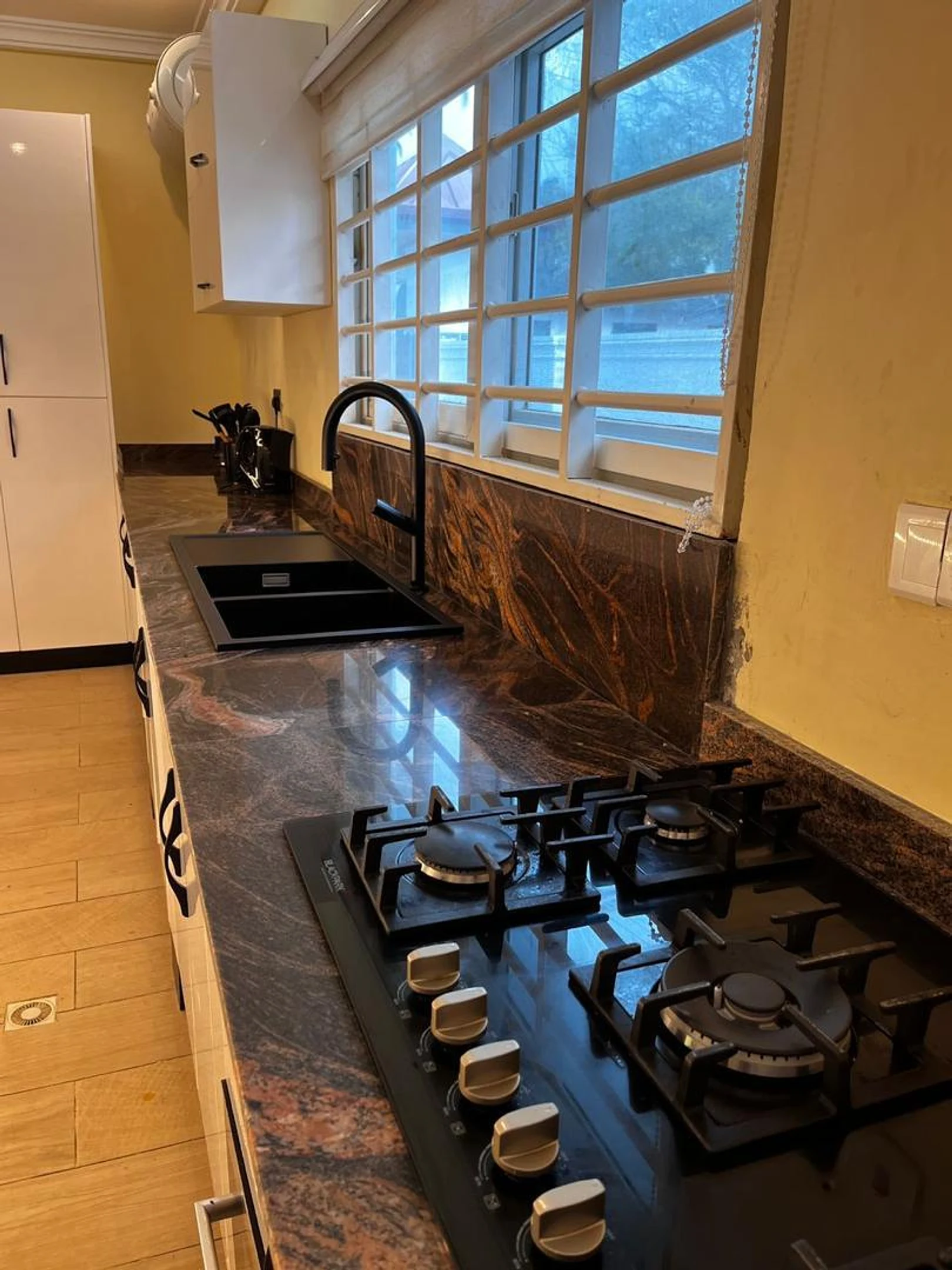 Five-burner gas hob with cast-iron grates and tiled backsplash